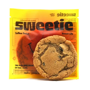 Cookie au caramel devant son emballage Sweetie jaune vif, avec l'inscription "Toffee Twist" et l’indication "CBD Full Spectrum - D9 THC < 0,3%".