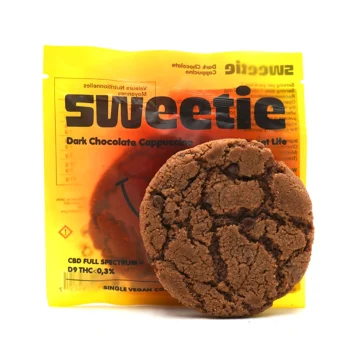 Cookie au chocolat noir positionné devant son sachet Sweetie, dont le design met en avant la saveur "Dark Chocolate Cappuccino" et la formule au CBD Full Spectrum.